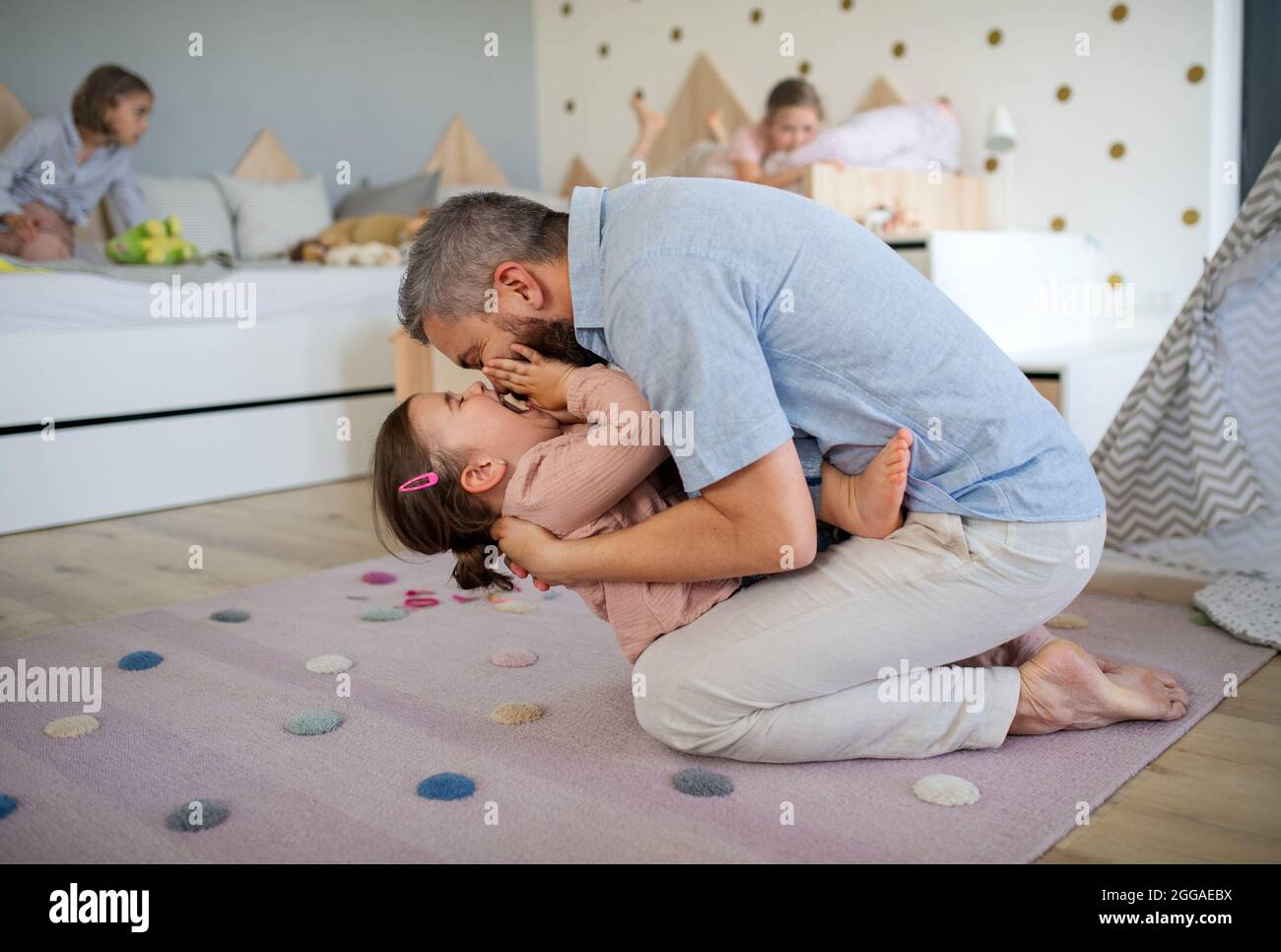 Father with daughters indoors at home, playing, laughing and having fun. Stock Photo
