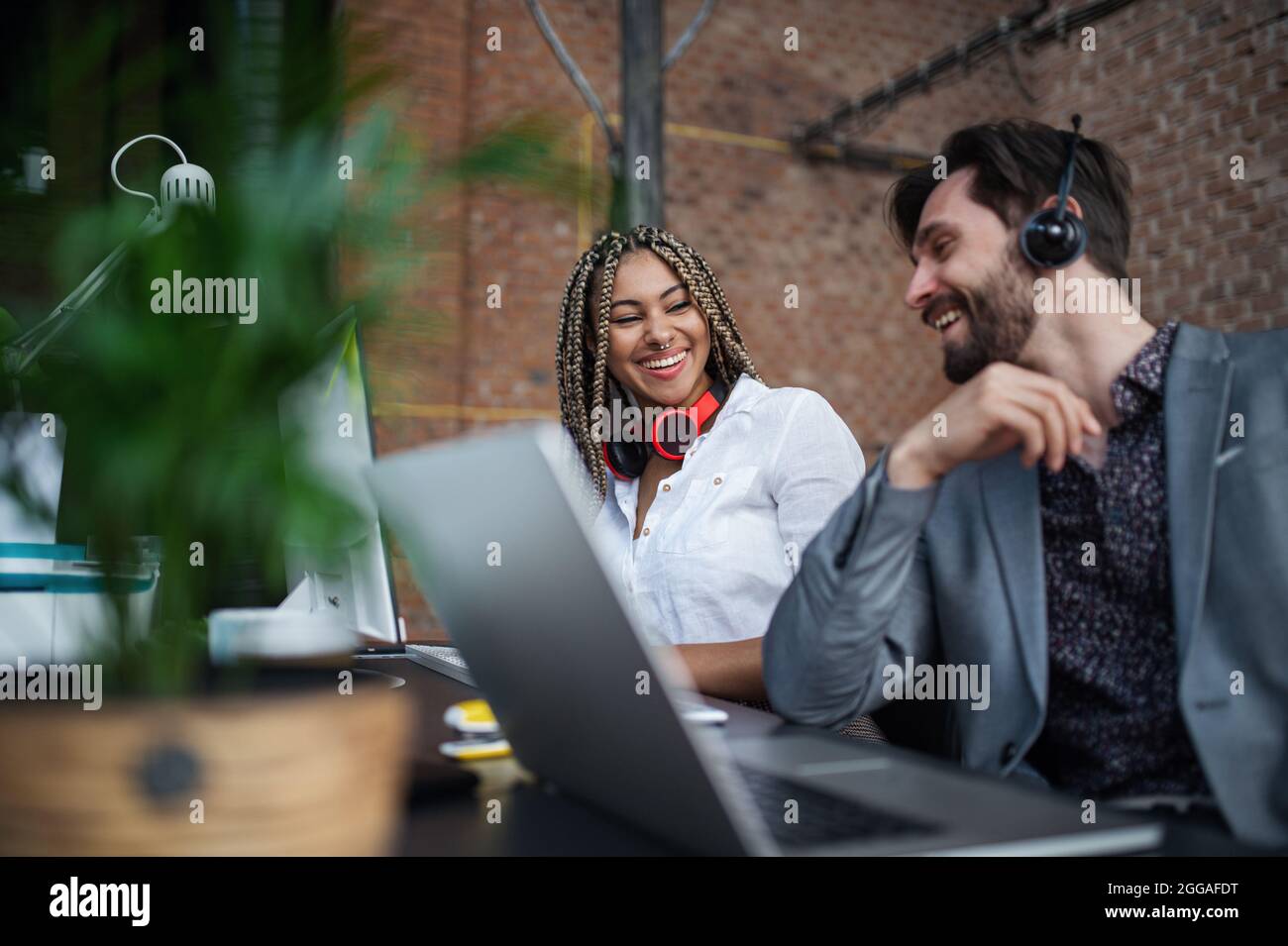 Cheerful young businesspeople sitting and working at desk in office ...