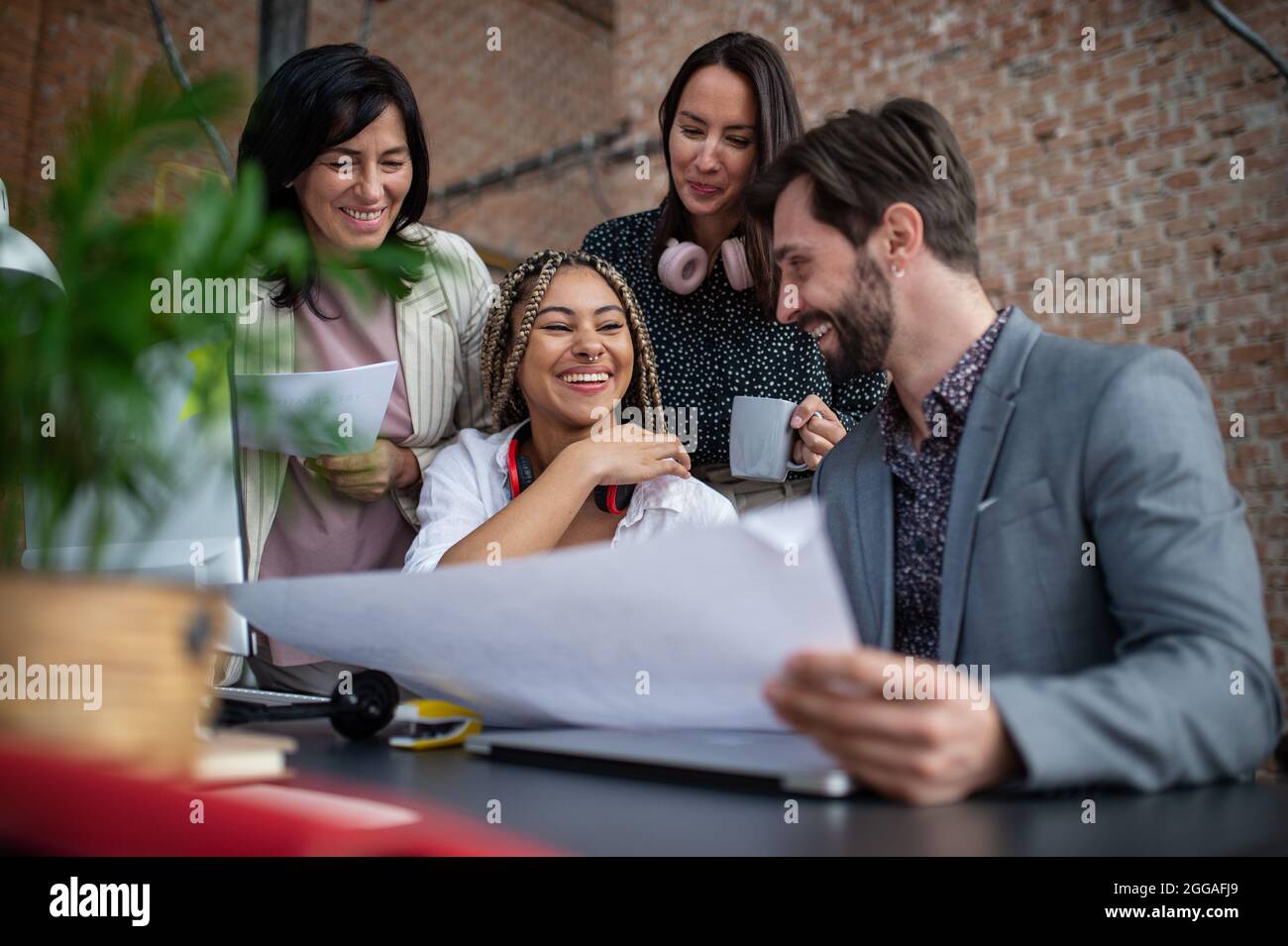 Cheerful young and old businesspeople sitting and working at desk in ...