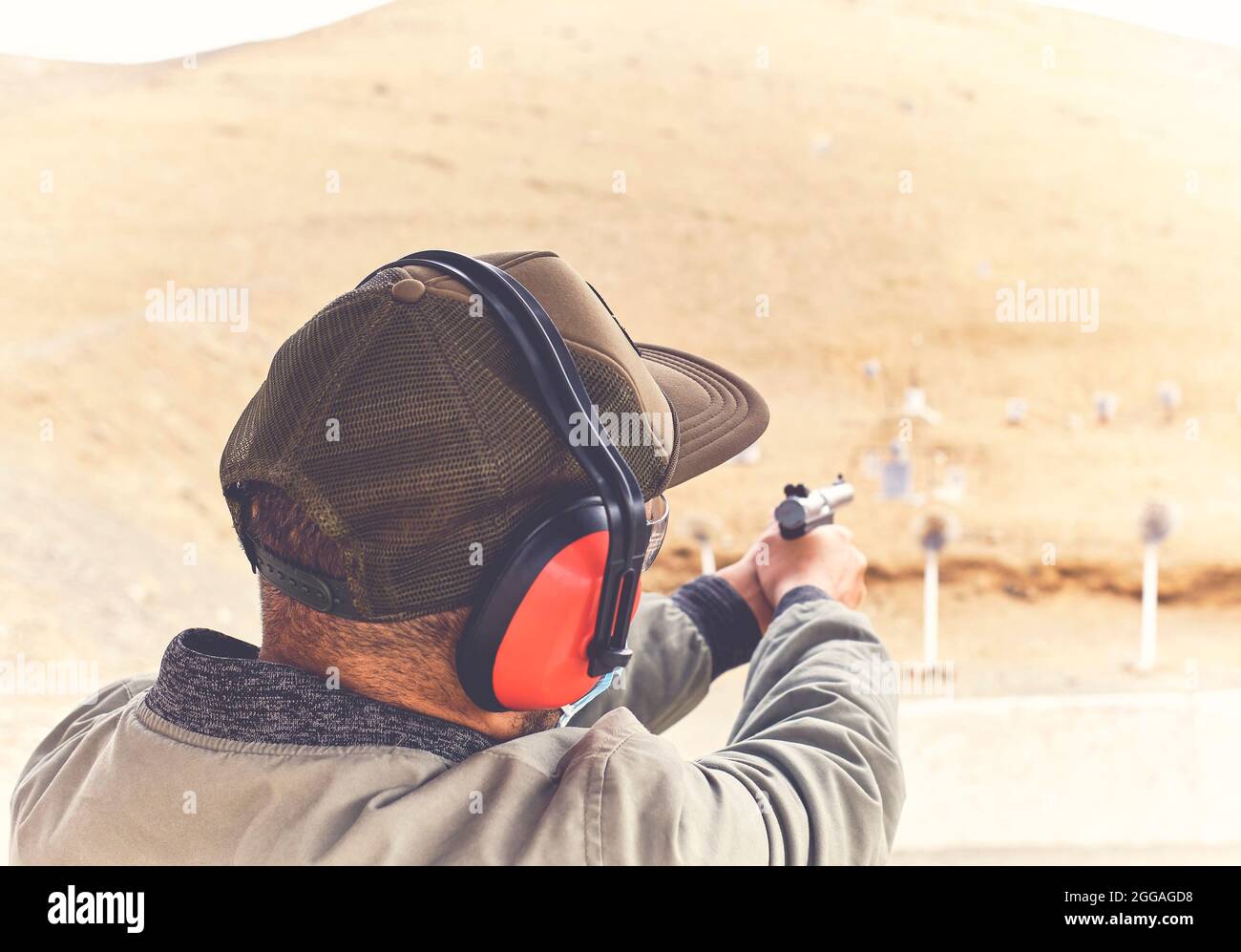 Man with hand gun aiming at shooting range and releasing stress