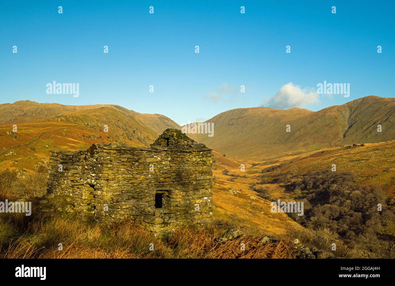 The upper section of the Troutbeck valley in the Lake District National Park with fells and an old abandoned barn, on a clear sunny winter day Stock Photo