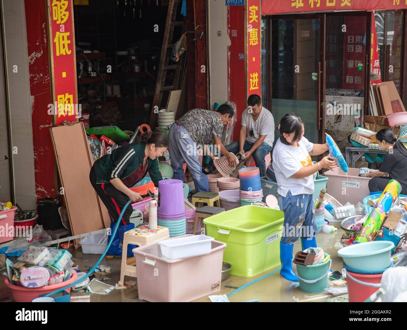 (210830) -- CHONGQING, Aug. 30, 2021 (Xinhua) -- Shop owners clean items after a flood in Wuxi County of Chongqing, southwest China, Aug. 30, 2021. Heavy rain has led to the flooding of four rivers in southwest China's Chongqing Municipality, and more than 2,000 people have been evacuated, according to Chongqing's flood control and drought relief headquarters. In Wuxi County, more than 260 shops were flooded due to constant rain. Local public security and emergency departments have jointly established rescue teams to help shop owners transfer materials and evacuate people who are trapped to Stock Photo