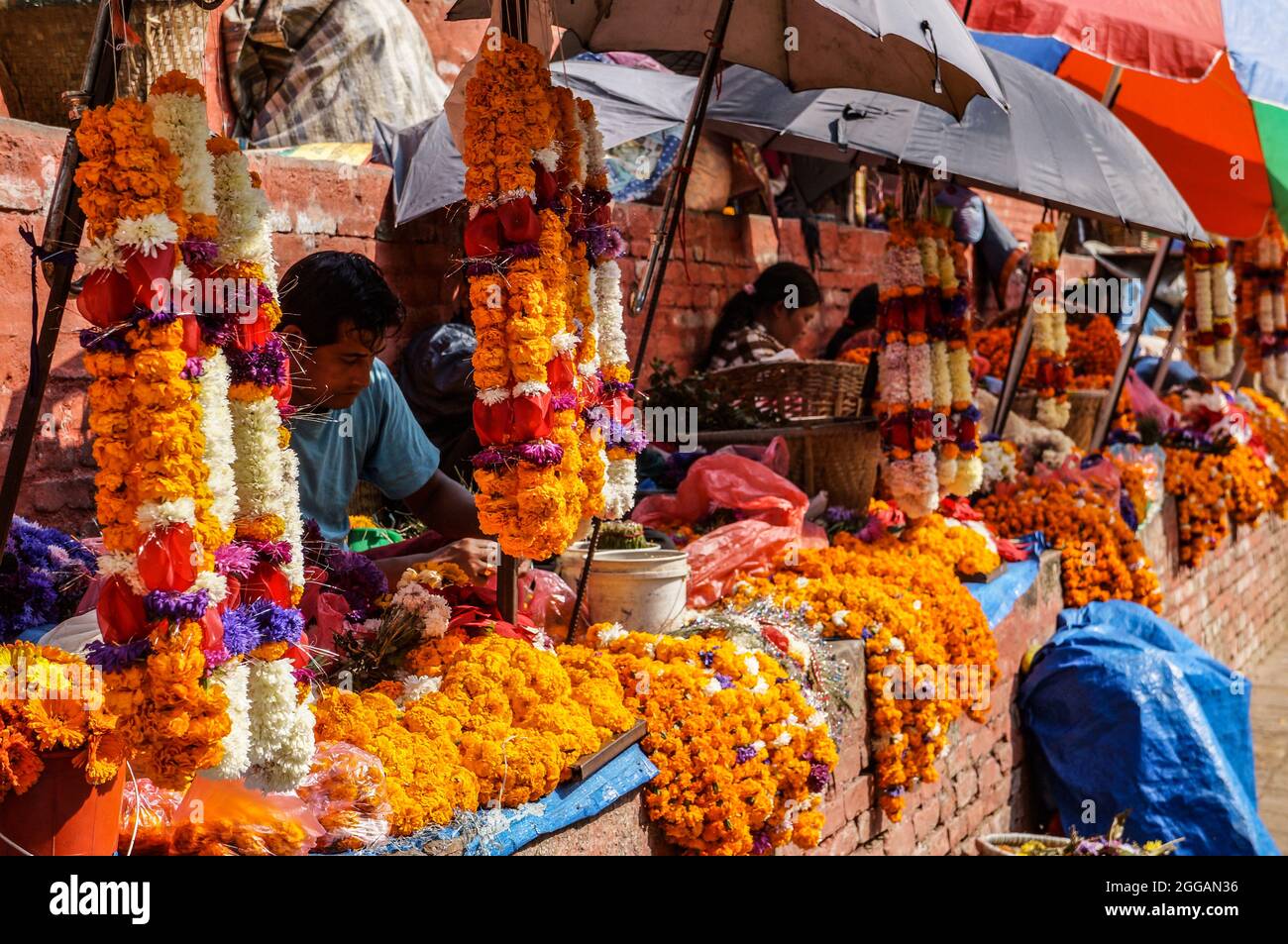 Marigold flower garland sellers on the stairs of the Maju Dega temple in Kathmandu Durbar Square, Nepal Stock Photo