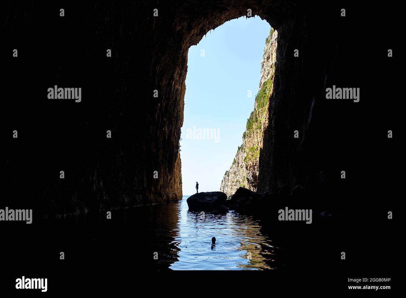 Tourist standing on a rock before jumping in a water in gigantic Haxhi