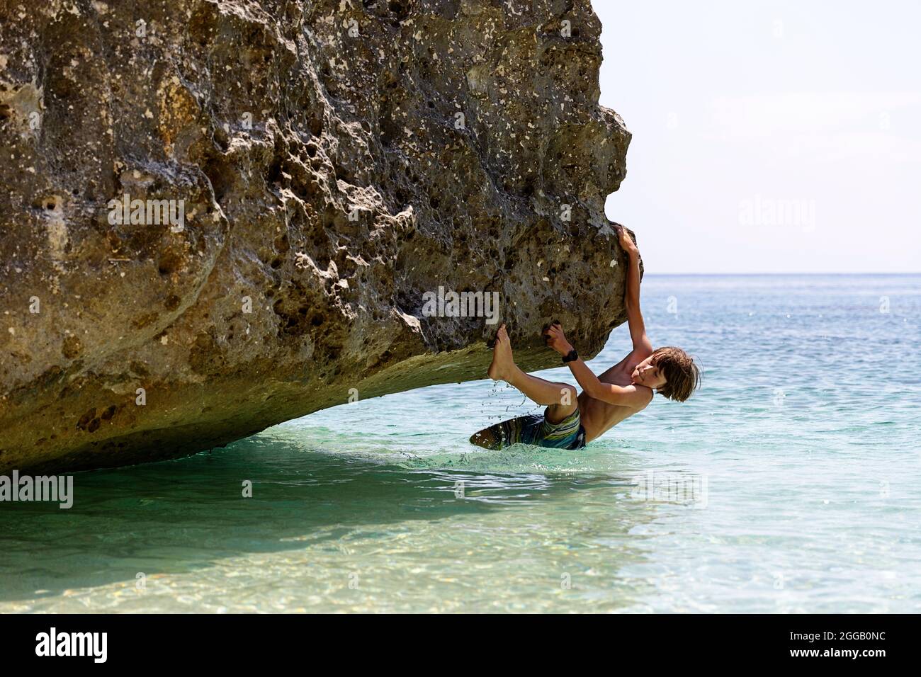 Boy tourist practising rock climbing on secluded beach in Grama bay on remote Karaburun