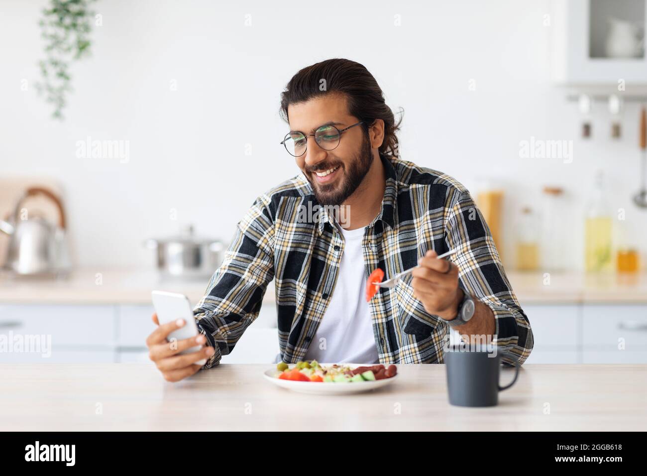 Handsome arab man using cellphone while having breakfast Stock Photo