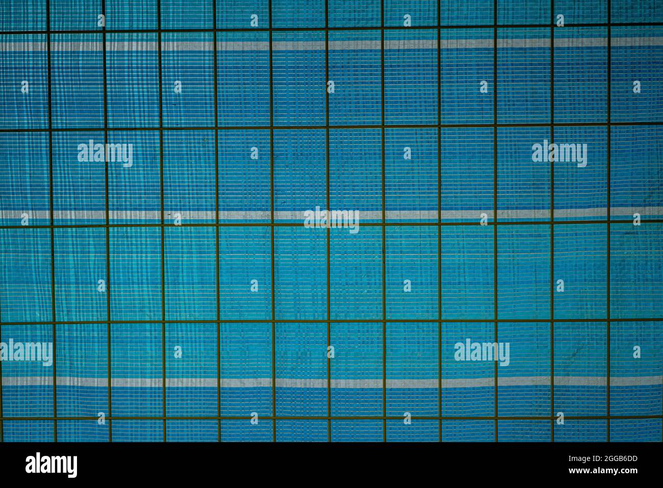 Metal wire fence on a blue plastic background. Stock Photo