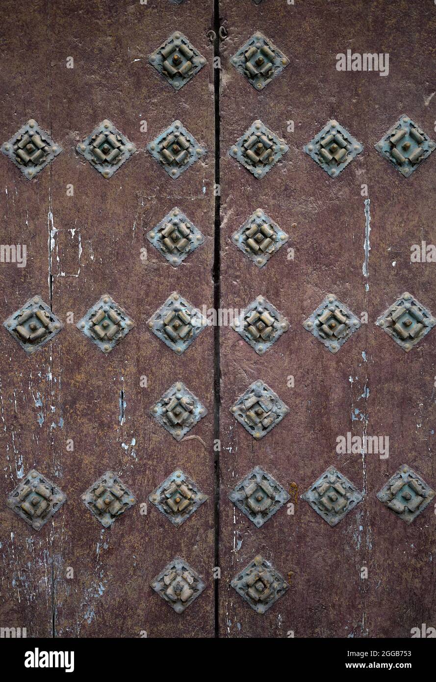 detail of an antique brown wooden double leaf door with metal nails or rivets Stock Photo