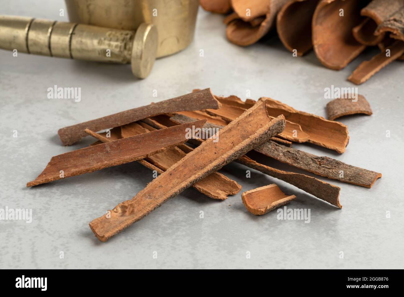 Heap of dried Cinnamon bark close up in front of a traditional mortar and pestle ready to ground Stock Photo