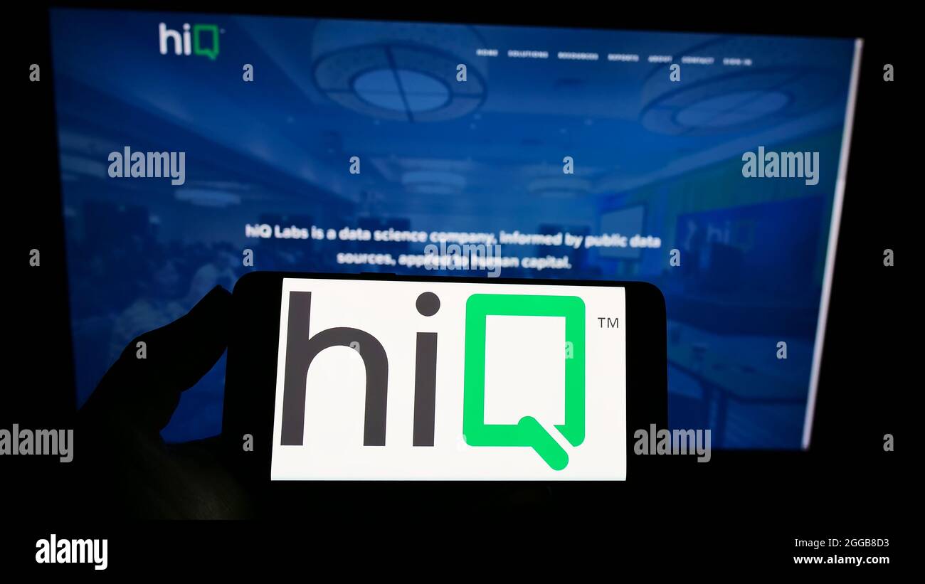 Person holding smartphone with logo of US data science company hiQ Labs Inc. on screen in front of website. Focus on phone display. Stock Photo
