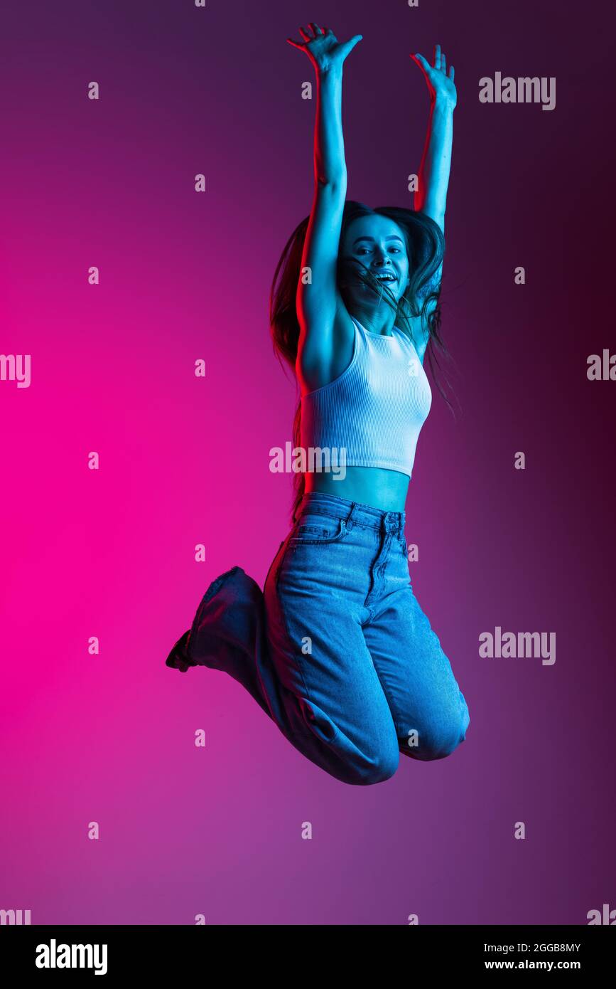 Full-length portrait of young beautiful girl jooyfully jumping with ...
