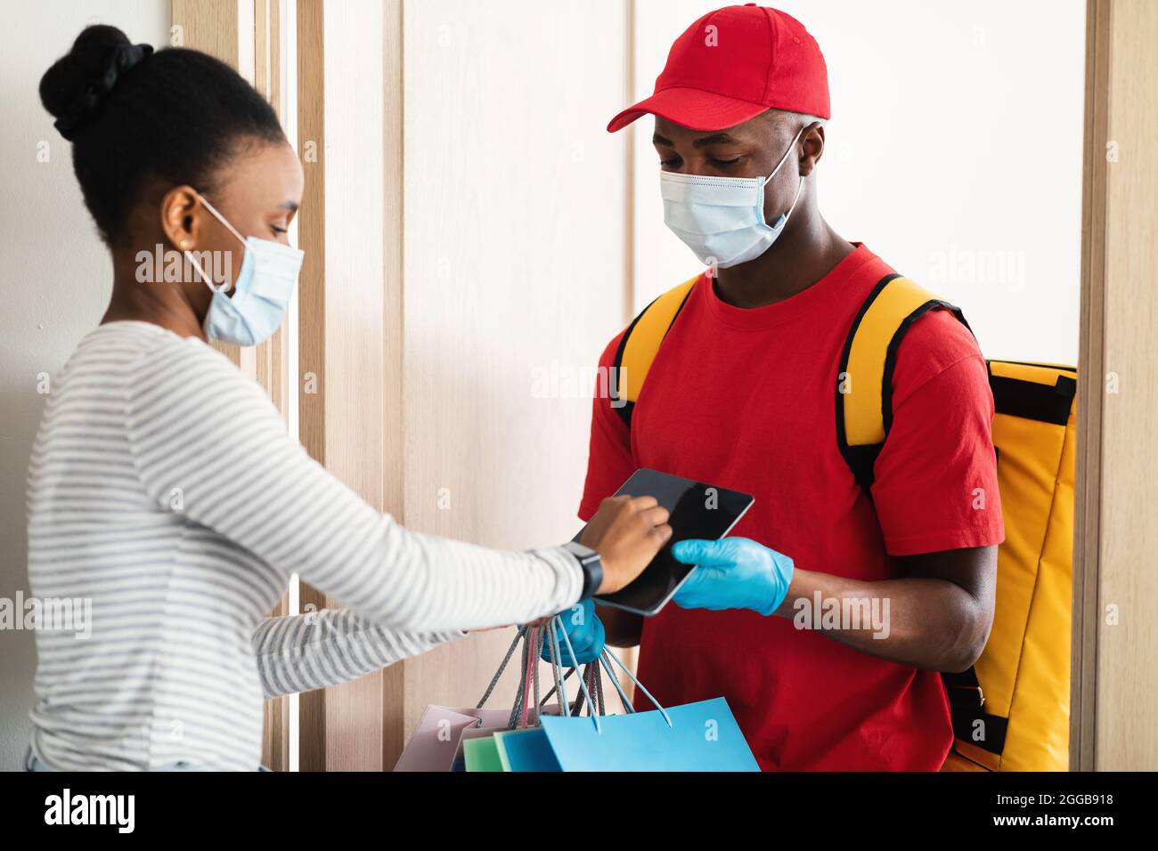 Lady Receiving Bags From Courier Scanning Fingerprint On Tablet Indoor Stock Photo