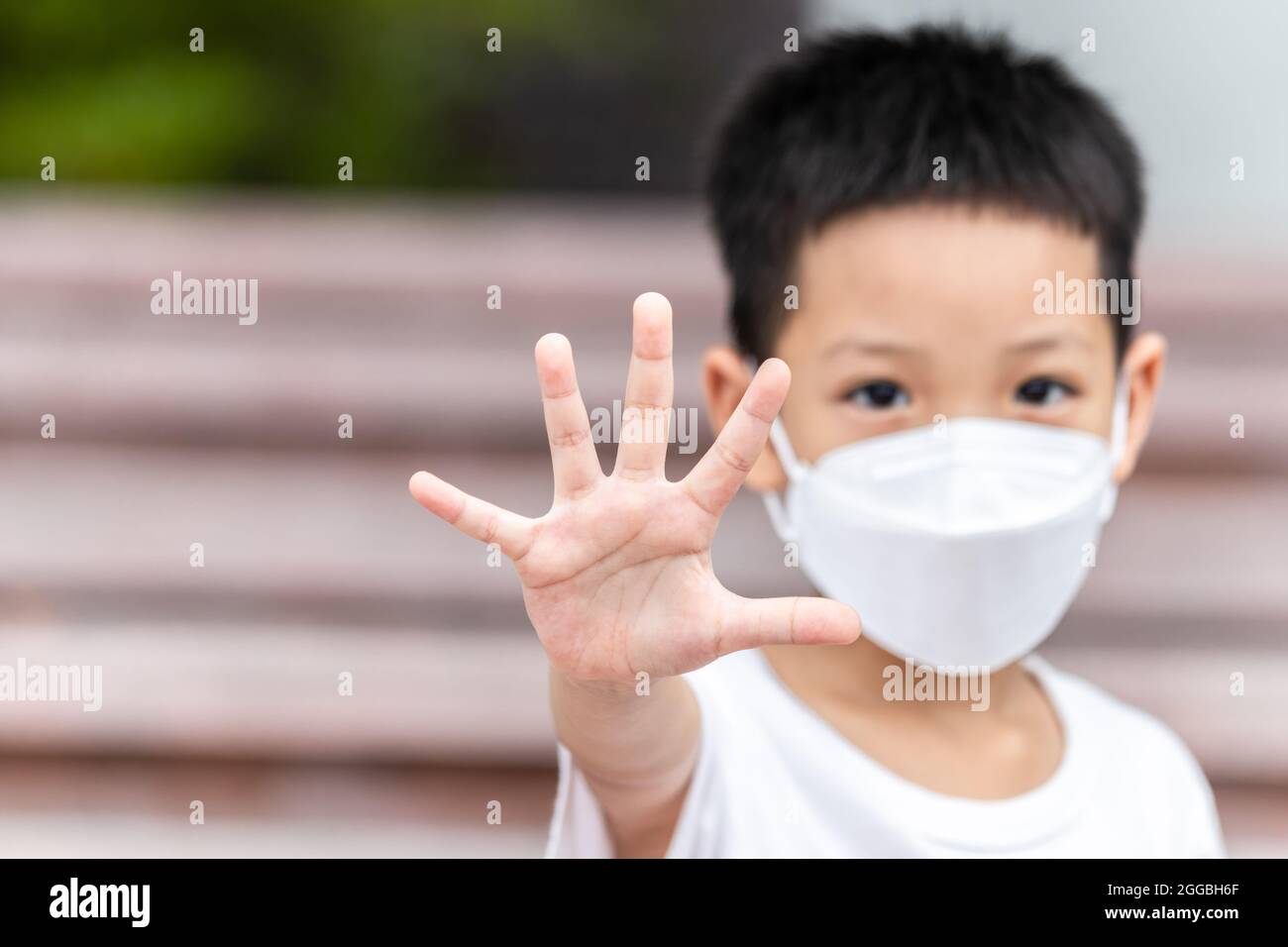 Asian little child showing stop his hand. A kid wearing face mask. Domestic Family violence concept. stop sign. focus hand. Stock Photo