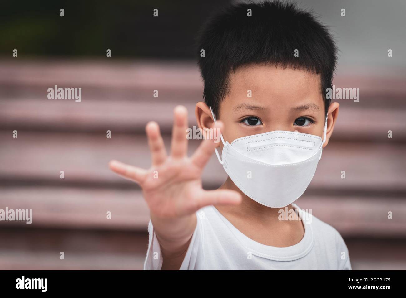 Asian little child showing stop his hand. A kid wearing face mask. Domestic Family violence concept. stop sign. focus face. Stock Photo