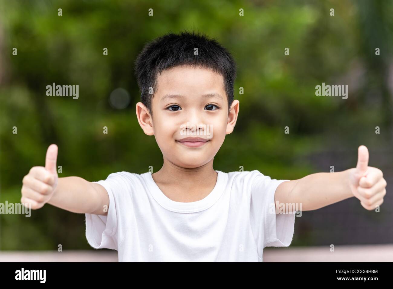 Little Asian boy success sign doing positive gesture with hand, thumbs up. Portrait of a smiling and happy little child showing hand ok. Stock Photo