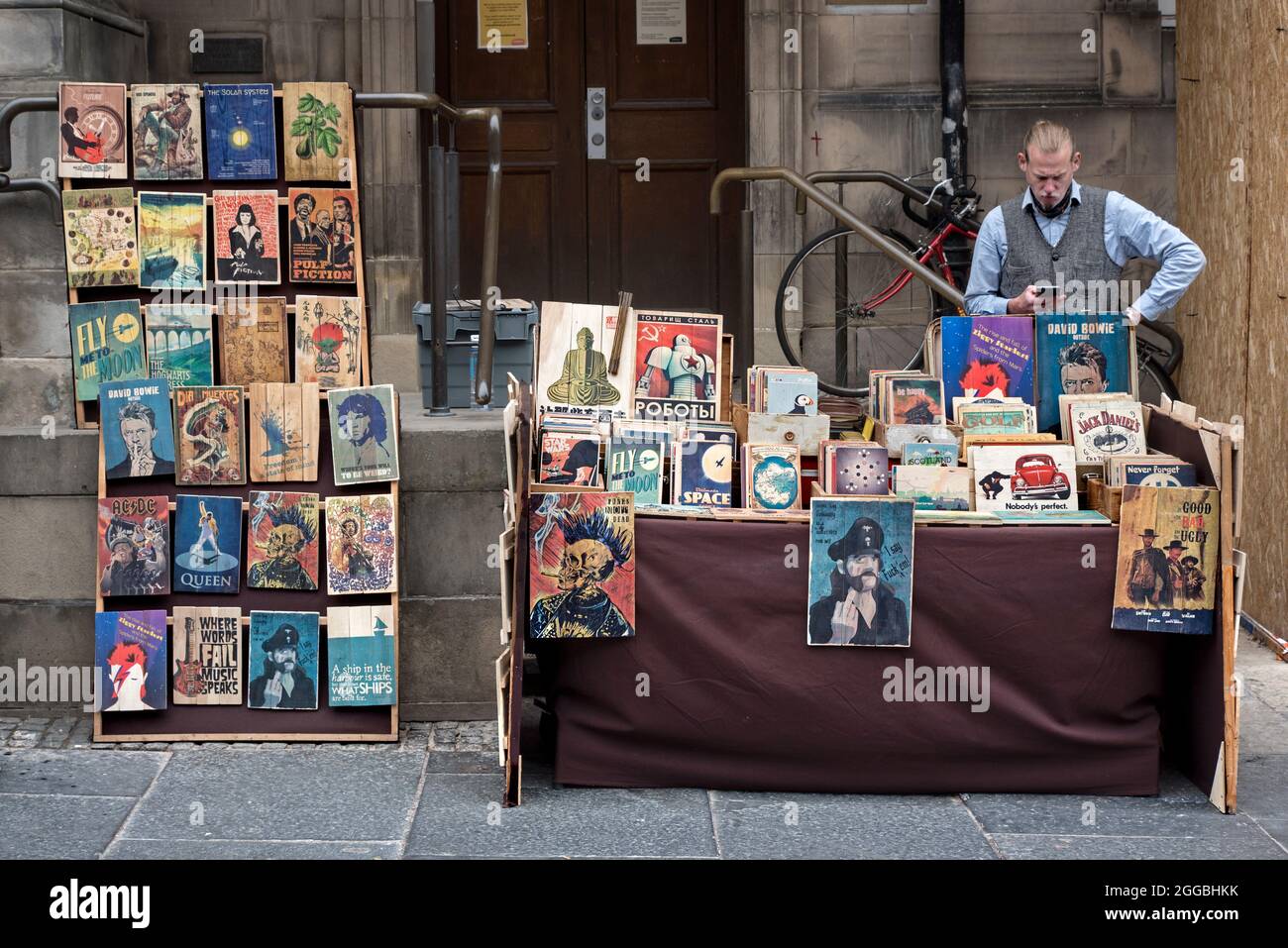 Stallholder selling wooden prints of popular culture at his stall on the Royal Mile in Edinburgh, Edinburgh, Scotland, UK. Stock Photo