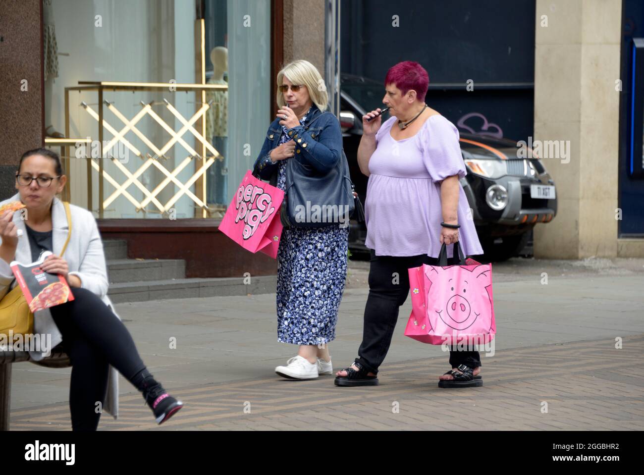 Women out shopping with pink pig bags. Stock Photo