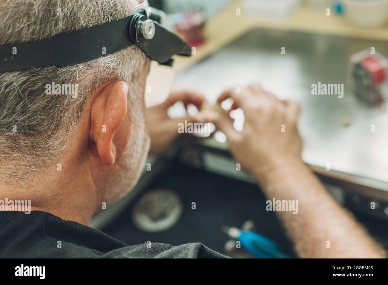 Selective focus on the head of a man working in a dental laboratory Stock Photo