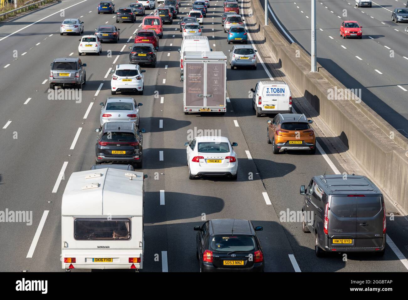 Section of M25 motorway in Longford near Heathrow Airport, UK, busy with traffic on a Bank Holiday August summer weekend. Caravan and cars Stock Photo