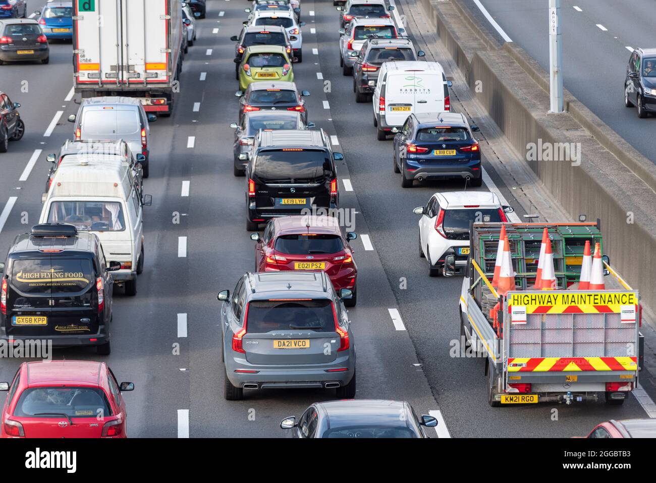 Section of M25 motorway in Longford near Heathrow Airport, UK, busy with traffic on a Bank Holiday August summer weekend. Highway Maintenance cones Stock Photo