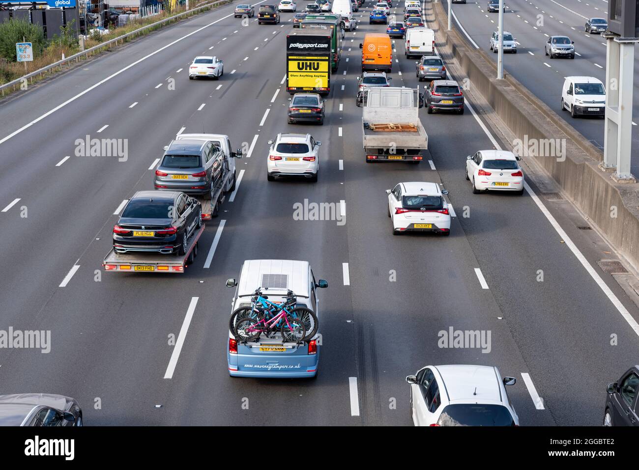 Section of M25 motorway in Longford near Heathrow Airport, UK, busy with traffic on a Bank Holiday August summer weekend. Campervan with bicycles Stock Photo