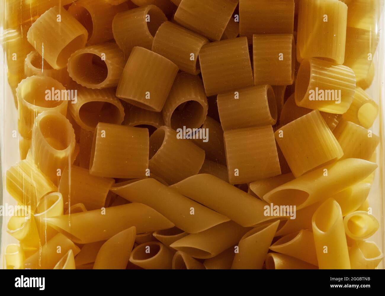 Pasta mix in a glass jar. Mezze maniche and Penne pasta Stock Photo