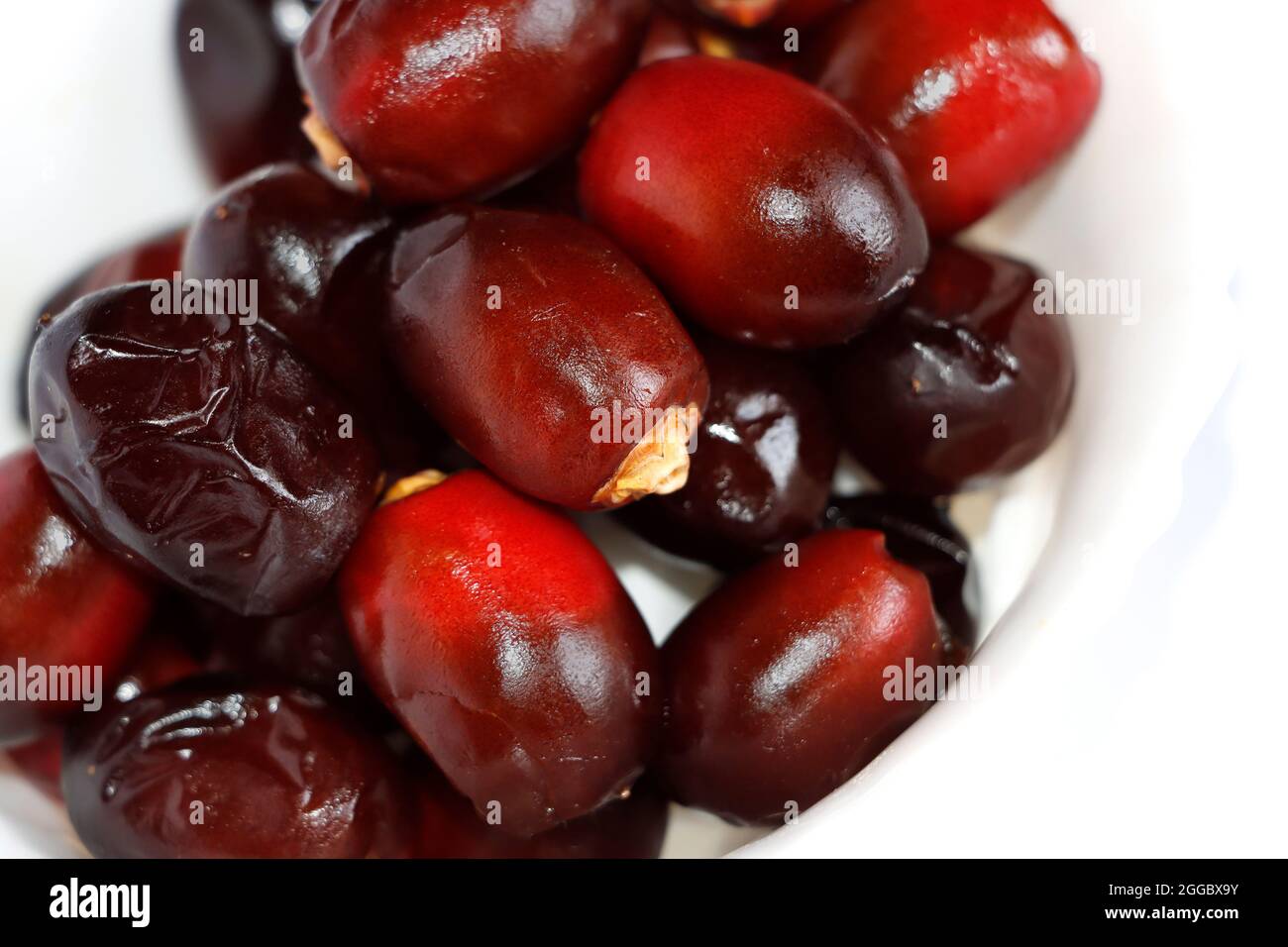 Closeup Image Of Arabic Dark Red Date Palm Fruits In White Background. Selective Focus Stock Photo