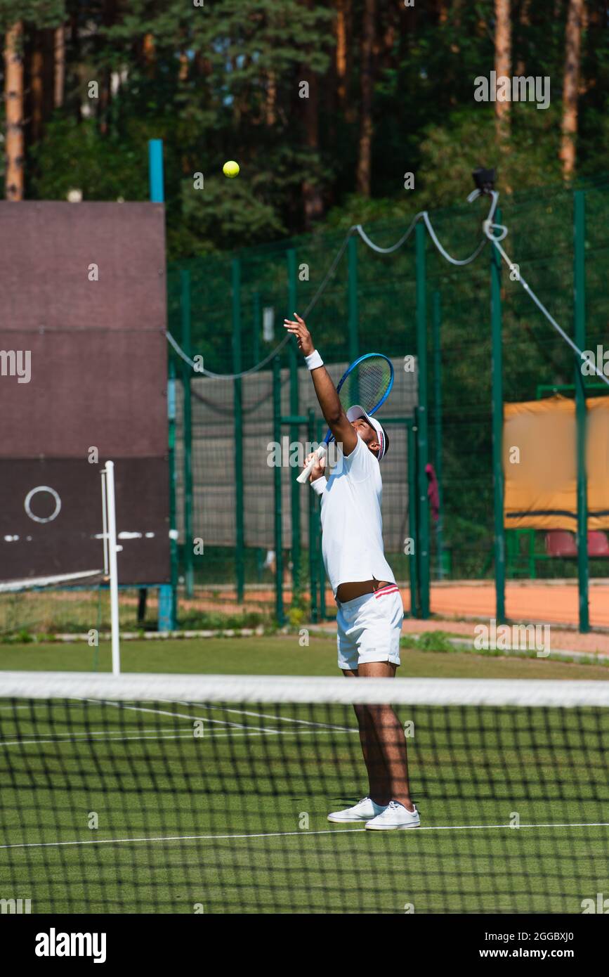 African american tennis player throwing ball near blurred net Stock Photo