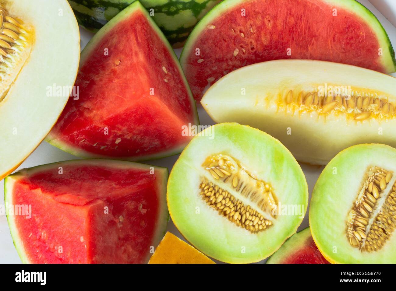 Close up of variety of cut melons on white background; summer fruit background Stock Photo