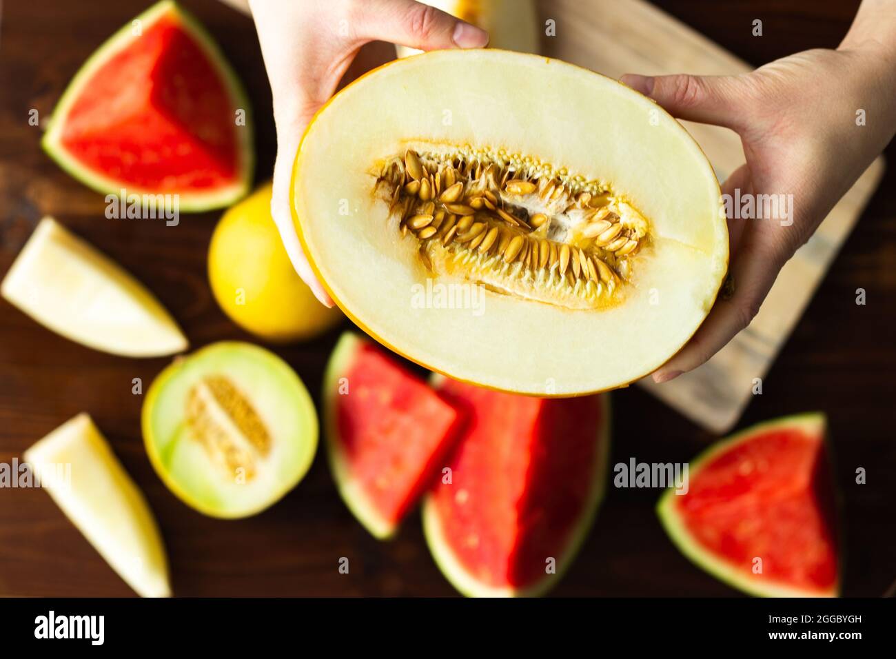 Top view of hands holding cut honeydew melon with seeds; variety of melon Stock Photo
