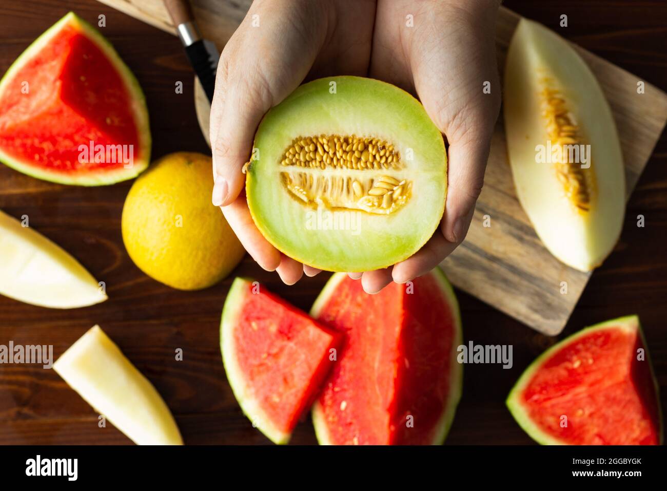 Top view of hands holding half a galia melon with seeds; variety of melons; summer fruits Stock Photo