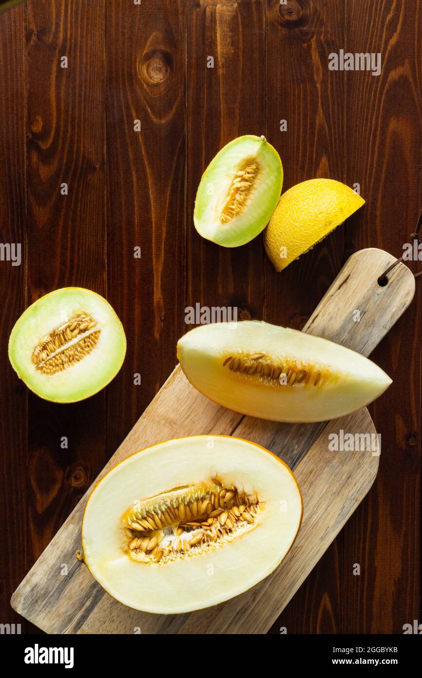 Top view of slices of honeydew melon on wooden cutting board and rustic wood with copy space Stock Photo