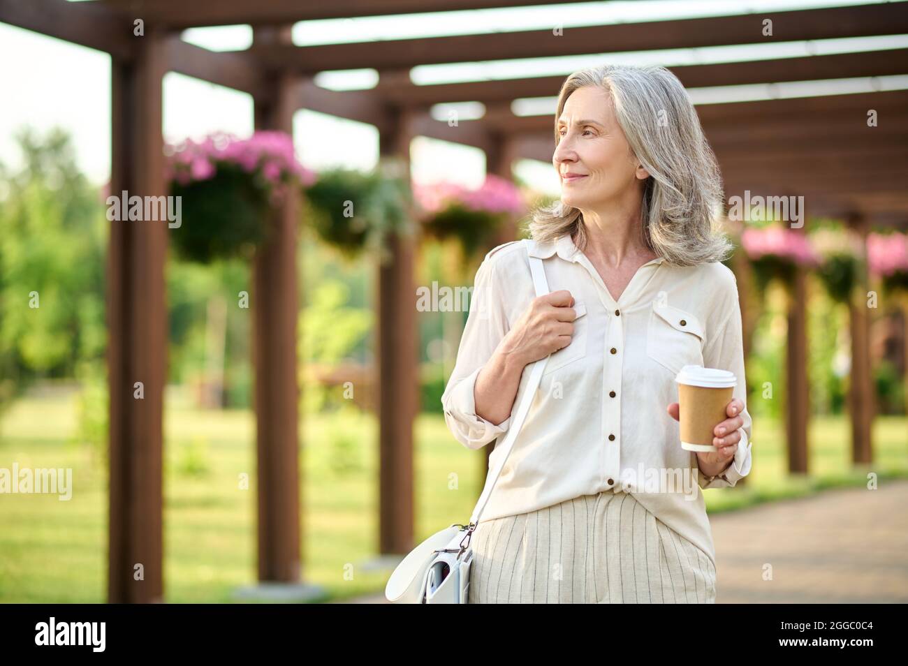 Woman with coffee looking to side in park Stock Photo