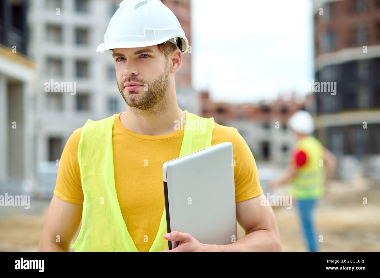 Handsome focused construction worker in headwear looking ahead Stock Photo