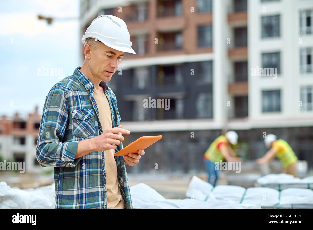 Handsome concentrated engineer reading an email on his gadget Stock Photo