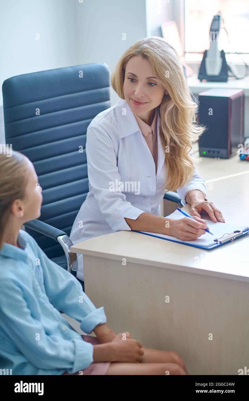 Focused doctor sitting at the desk during the pediatric consultation Stock Photo
