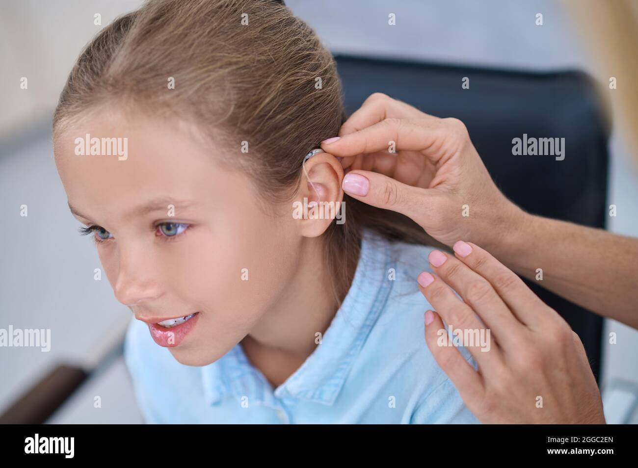 Female patient having a hearing device attached behind her ear Stock