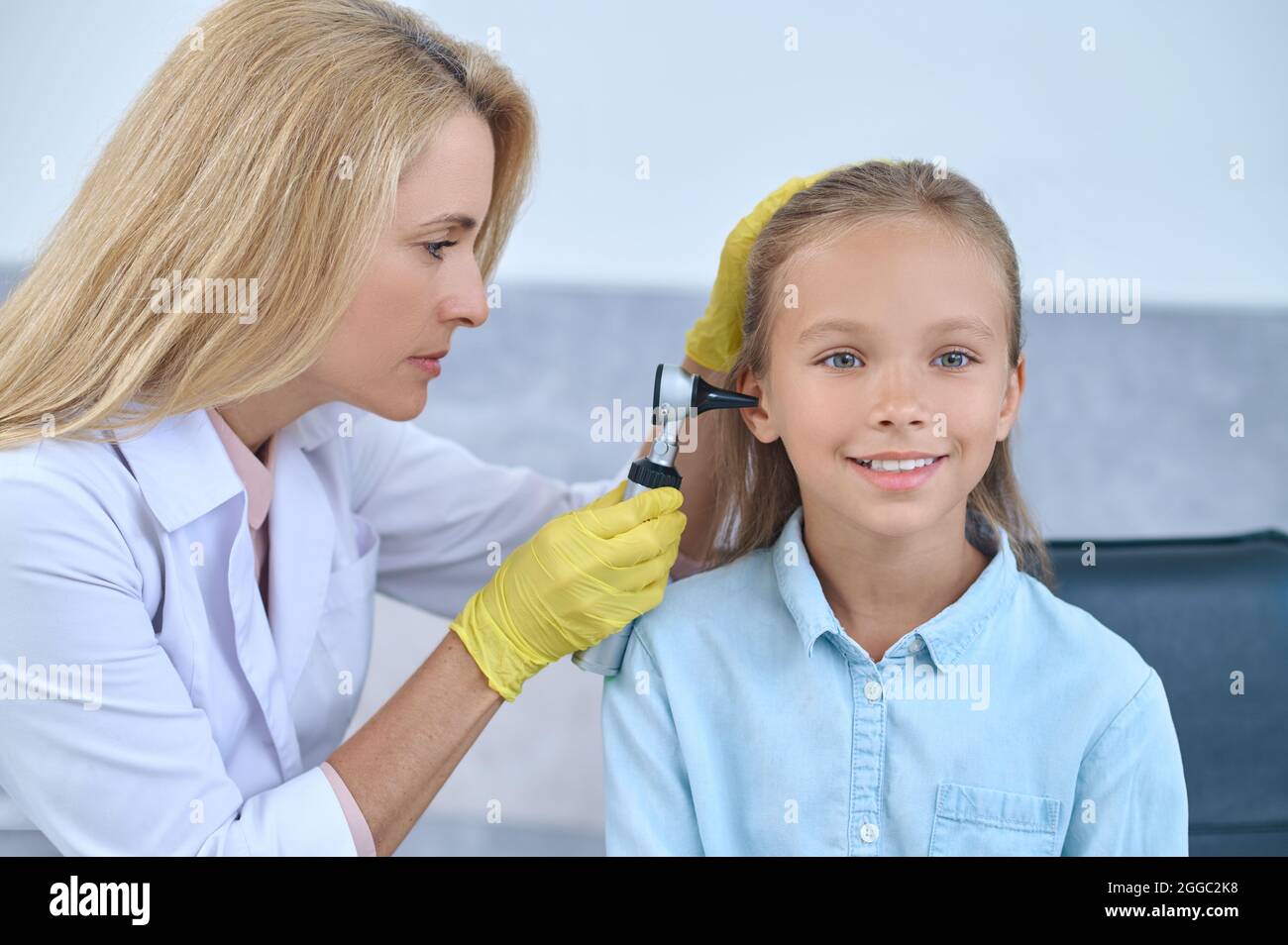 Doctor examining the young girls ear with a medical device Stock Photo