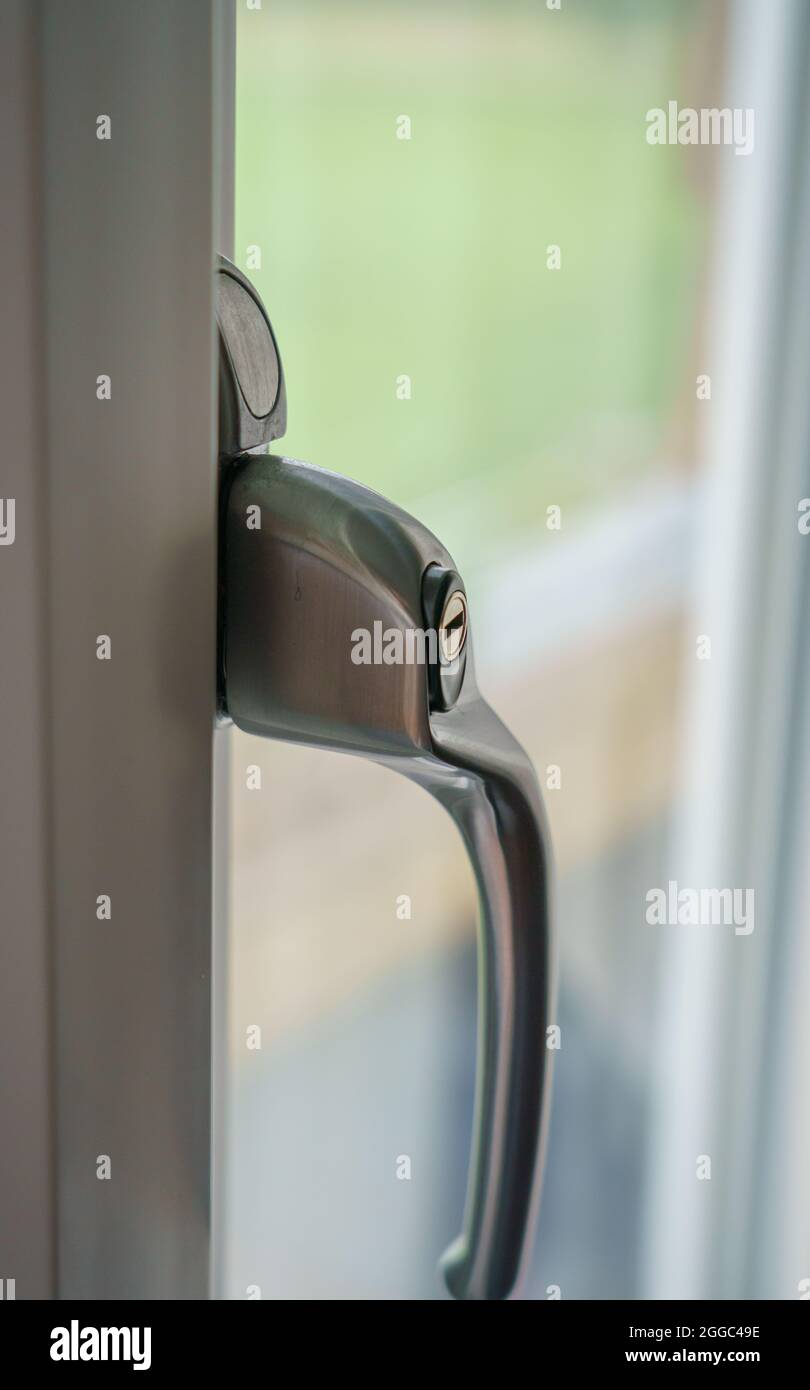 close up of modern double glazed matt chrome metal double glazed window handle with key lock
