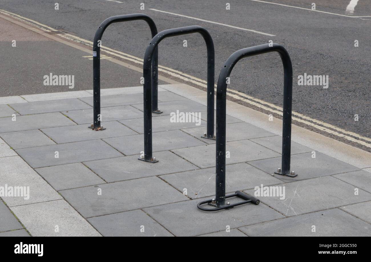 Black cycle rack or stand on pavement beside road with double yellow line Stock Photo