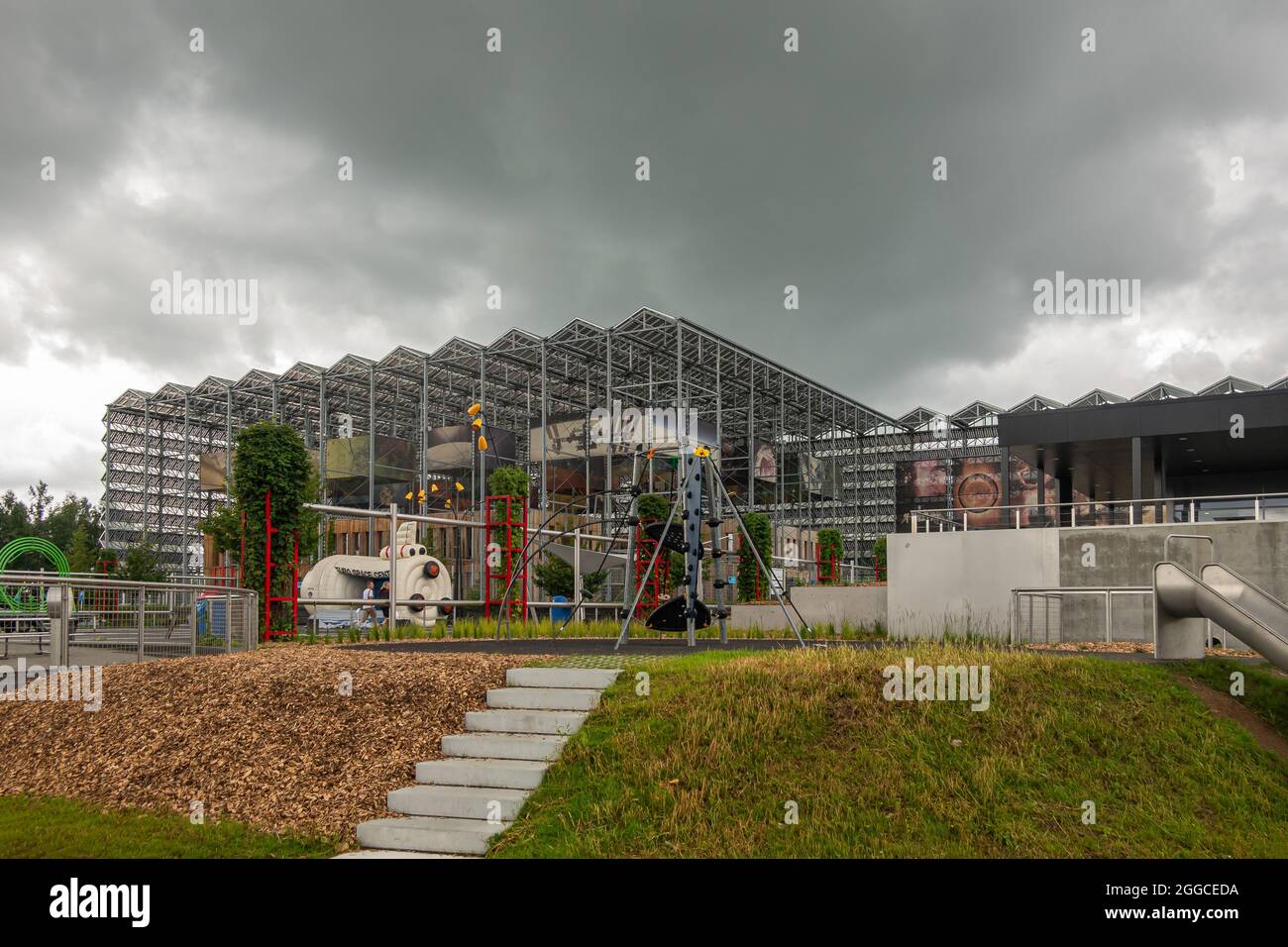 Transinne, Wallonia, Belgium - August 10, 2021: Euro Space Center modern architecture open structure under rainy sky behind grass and brown wood ships Stock Photo