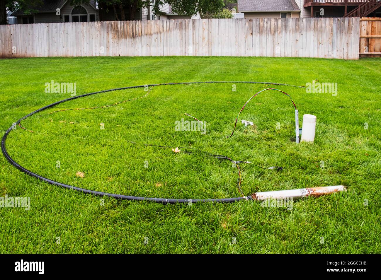 Faulty in ground lawn sprinkler pump and burnt wiring lying in tall fescue grass in the process of being changed out for a new pump. Kansas, USA. Stock Photo