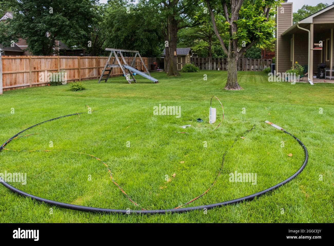 Faulty in ground lawn sprinkler pump and burnt wiring lying in tall fescue grass in the process of being changed out for a new pump. Kansas, USA. Stock Photo