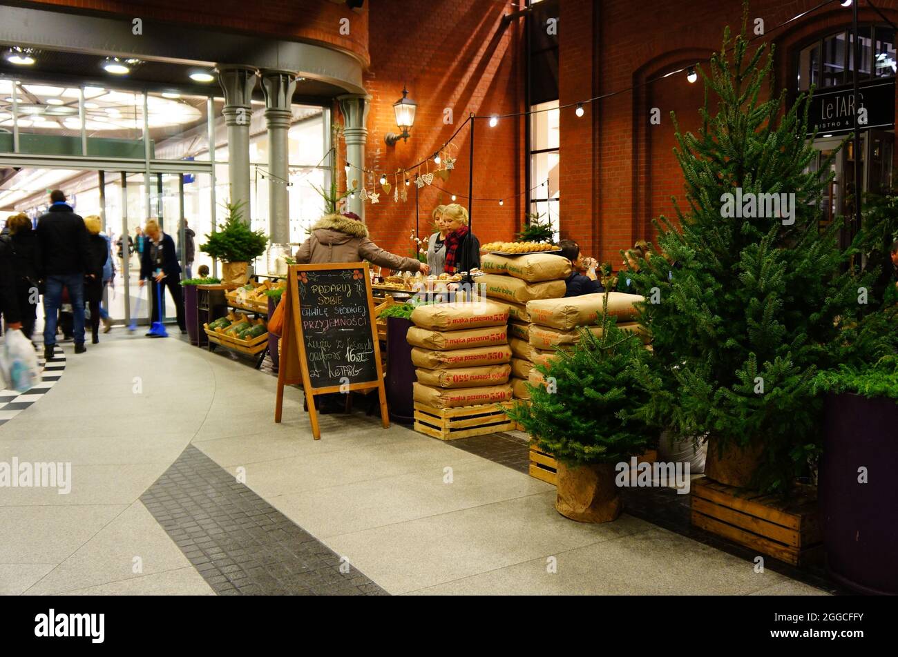 POZNAN, POLAND - Dec 14, 2014: A female selling fresh bread behind a stand next to trees in the Stary Browar shopping mall Stock Photo