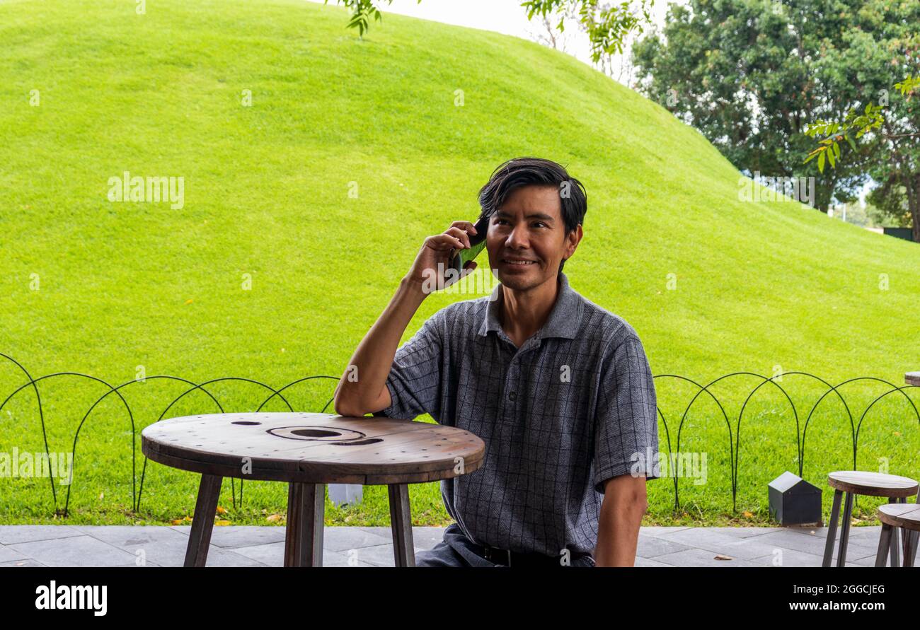 Hispanic man using cellphone in the park Stock Photo