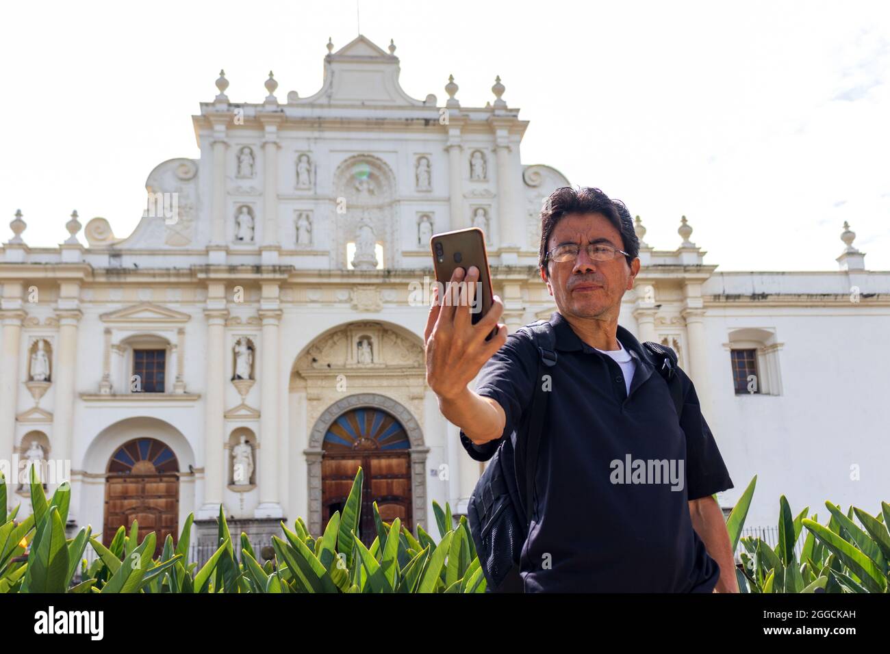 hispanic man taking a selfie in front of the main cathedral of antigua guatemala Stock Photo