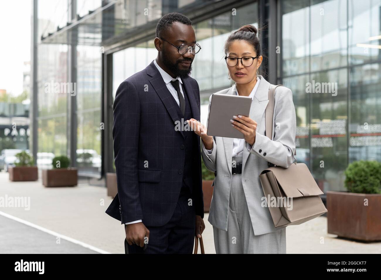 Two elegant multiracial colleagues preparing presentation in urban environment Stock Photo