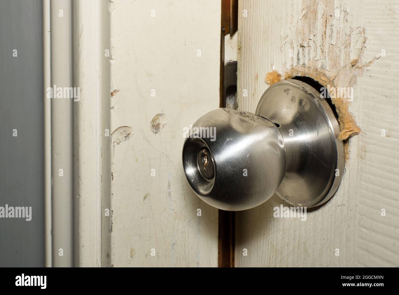 Broken modern doorknob closeup with signs of forced entry, criminal activity and door slightly open. Stock Photo