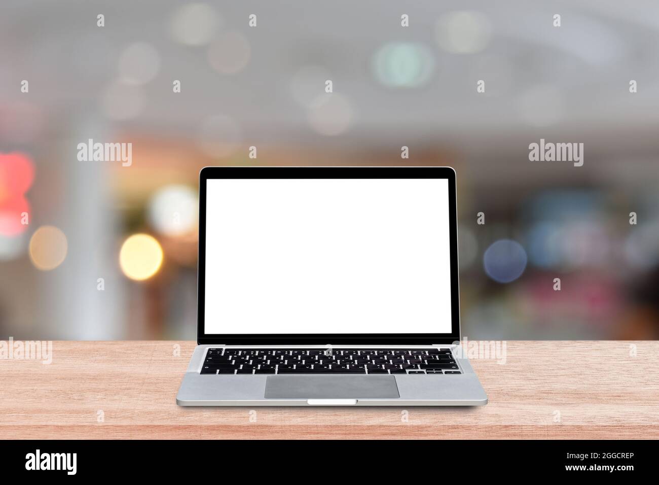 Laptop computer with blank screen on wood table over blur shopping mall ...