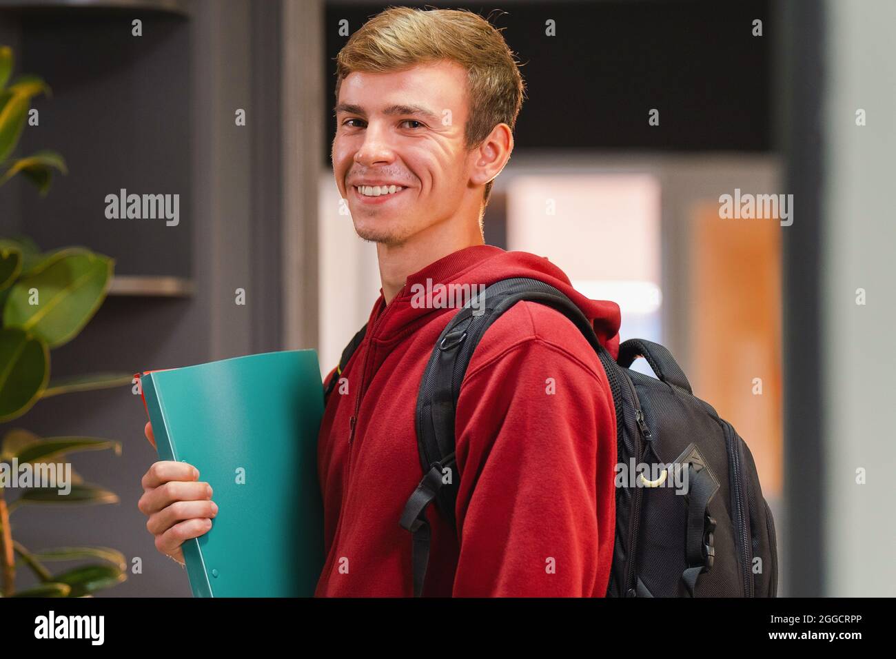 Side view photo of a happy student man in university wearing red hoodie ...